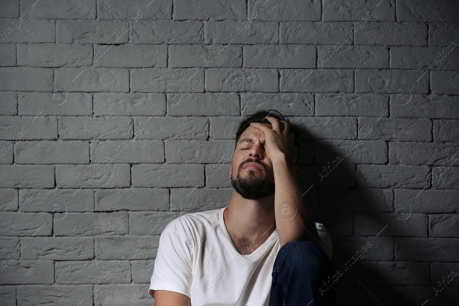 Photo of Lonely man suffering from depression near brick wall