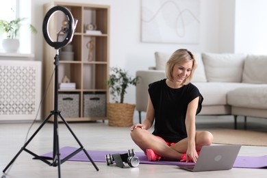 Smiling sports blogger streaming online fitness lesson with smartphone at home