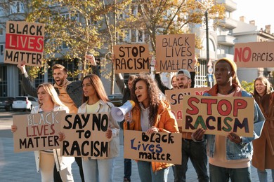 Photo of Protesters demonstrating different anti racism slogans outdoors. People holding signs with phrases