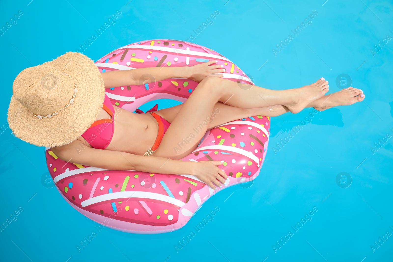 Photo of Young woman wearing stylish pink bikini on inflatable ring in swimming pool, above view