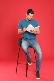 Handsome man reading book on color background