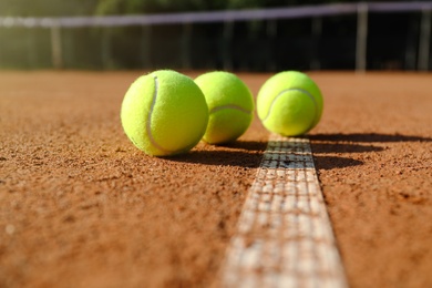 Bright yellow tennis balls on clay court