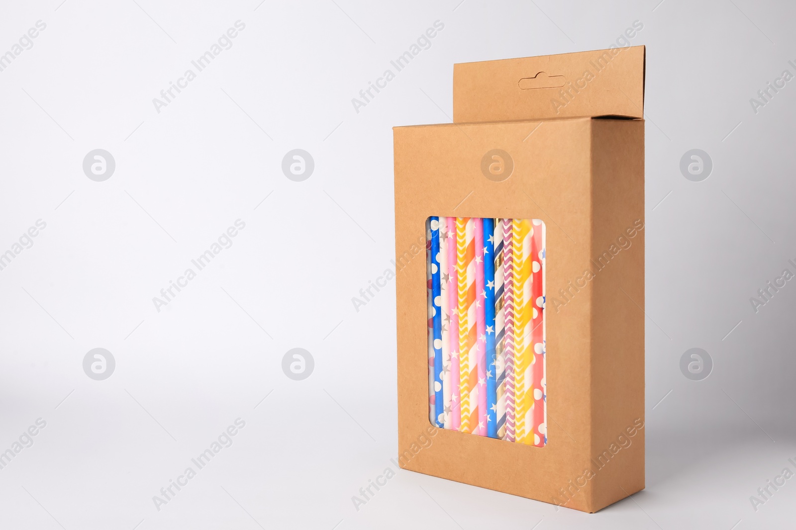 Photo of Box with many paper drinking straws on light grey background. Space for text