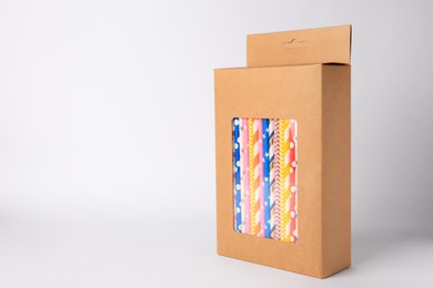 Box with many paper drinking straws on light grey background. Space for text