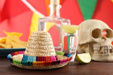 Photo of Mexican sombrero hat, human scull and tequila on wooden table