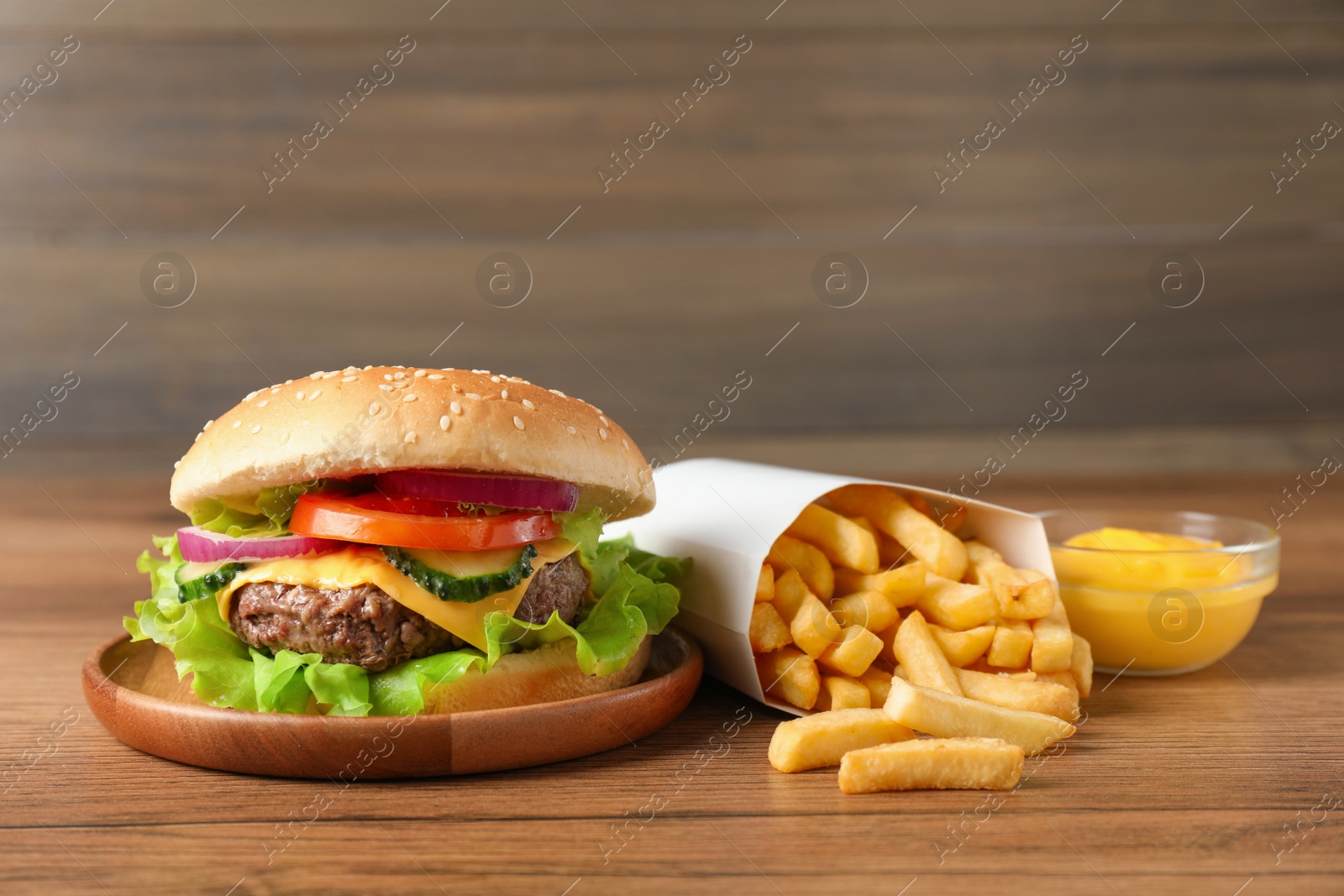 Photo of Delicious burger, sauce and french fries served on wooden table
