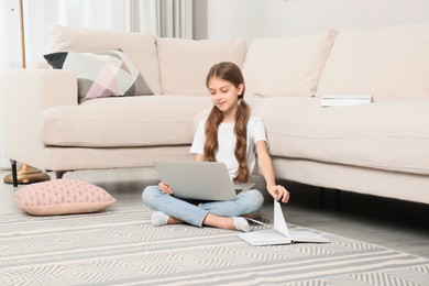 Photo of Girl with laptop and book sitting on floor at home