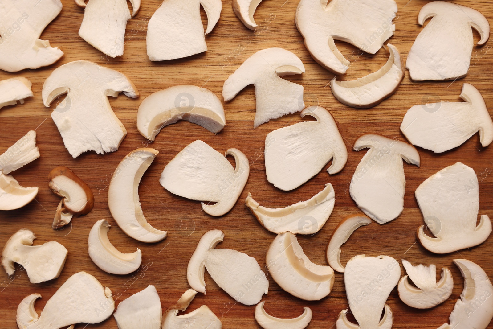 Photo of Slices of mushrooms on wooden board prepared for natural dehydration, closeup