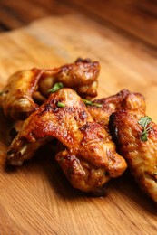 Photo of Delicious grilled chicken wings on wooden board, closeup