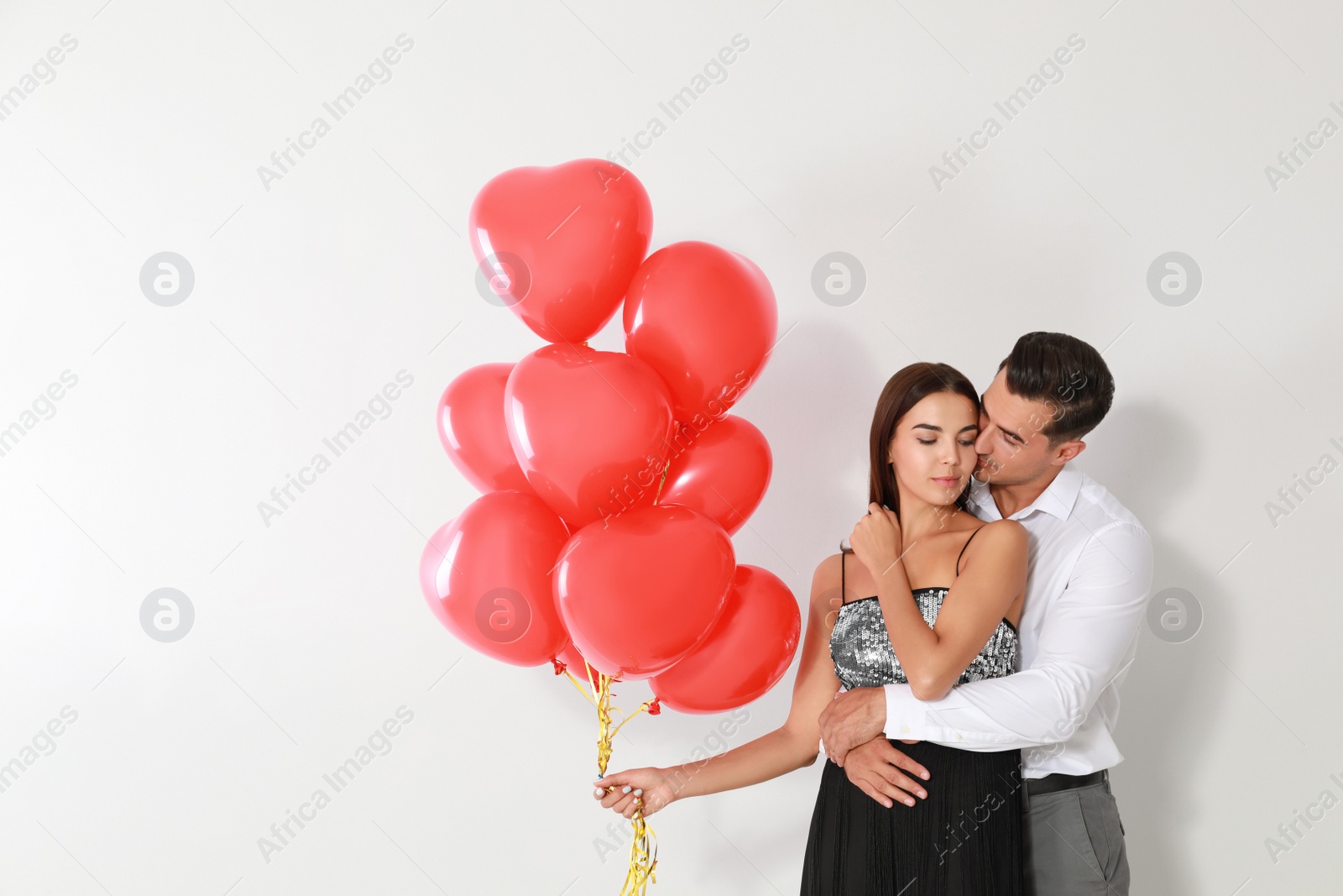 Photo of Beautiful couple with heart shaped balloons on light background, space for text