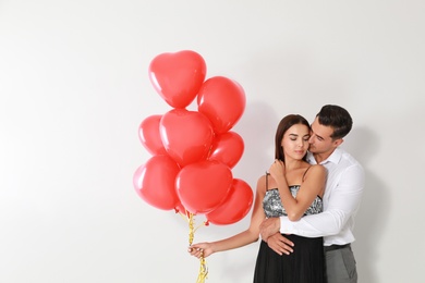 Photo of Beautiful couple with heart shaped balloons on light background, space for text
