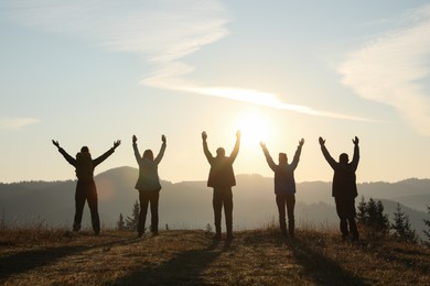 Photo of Group of people enjoying sunrise in mountains, back view