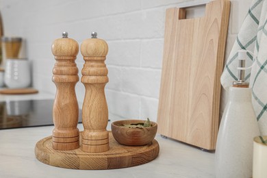 Photo of Wooden salt and pepper shakers, bowl with bay leaves on white countertop, space for text