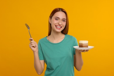 Young woman with piece of tasty cake on orange background