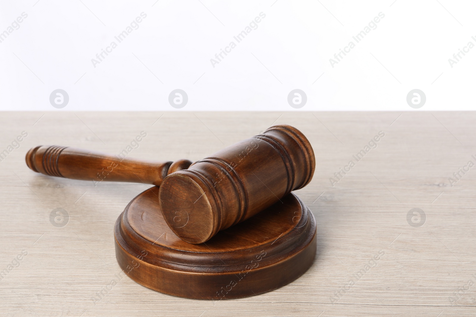 Photo of Wooden gavel on light table against white background