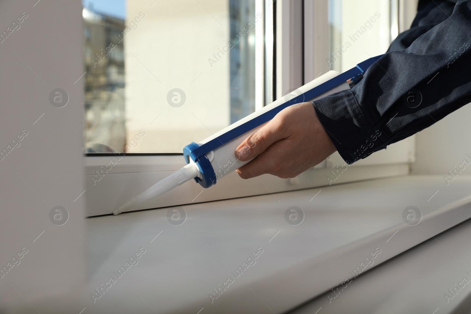 Photo of Construction worker sealing window with caulk, closeup