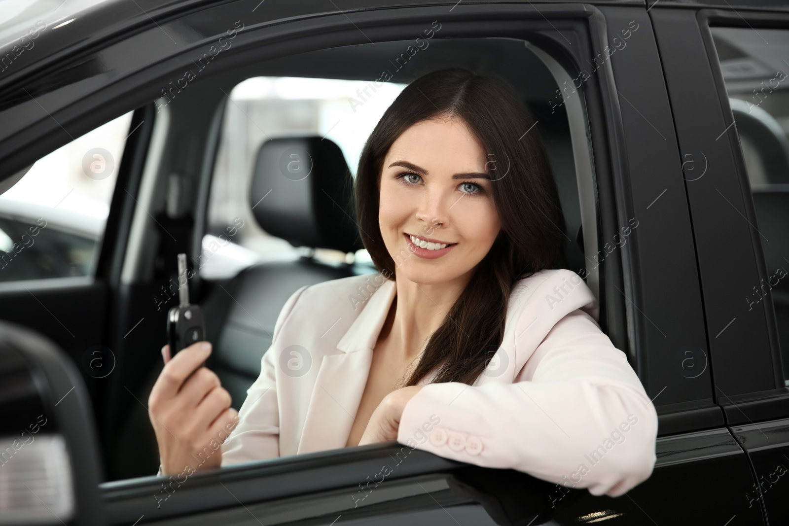 Photo of Young woman with key sitting in driver's seat of auto. Buying new car