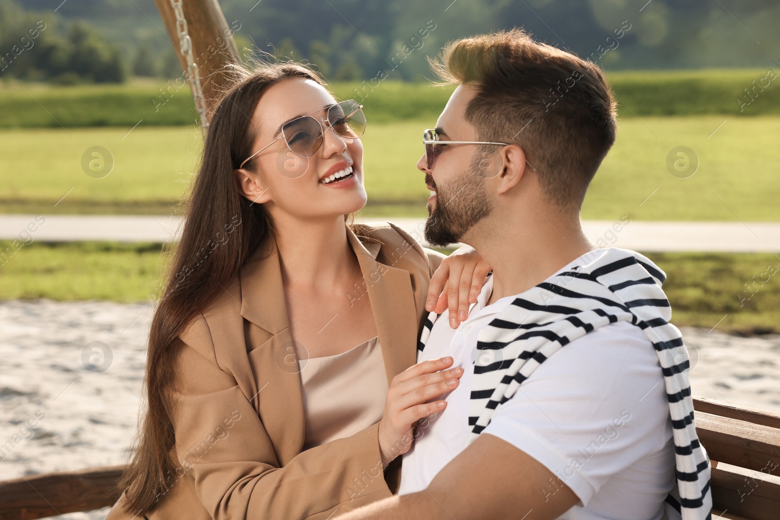 Photo of Romantic date. Beautiful couple spending time together on swing bench outdoors