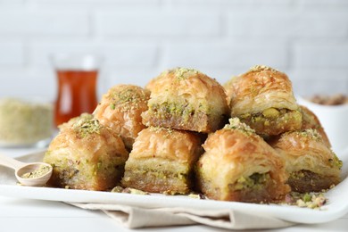 Delicious fresh baklava with chopped nuts on white table, closeup. Eastern sweets