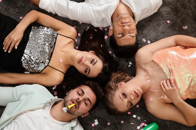 Photo of Group of friends sleeping on messy floor after party, top view