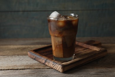 Photo of Glass of delicious iced coffee with milk on wooden table