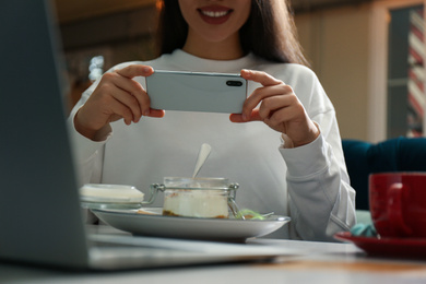 Photo of Blogger taking picture of dessert at table in cafe, closeup