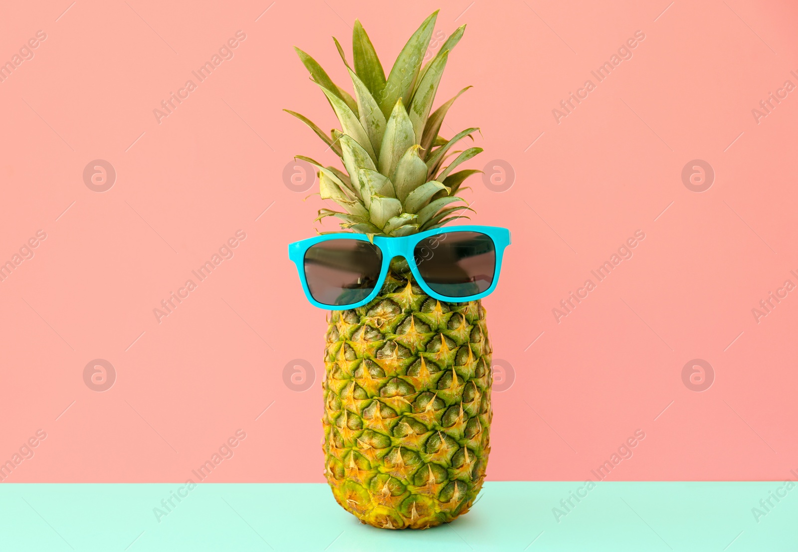 Photo of Fresh ripe pineapple with sunglasses on color background