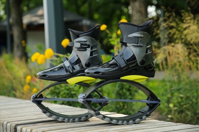 Stylish kangoo jumping boots on wooden bench outdoors