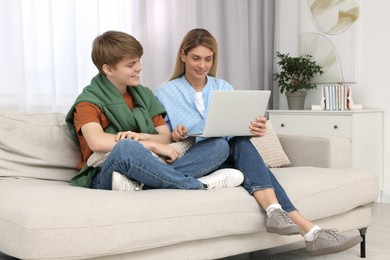 Happy teenage son and his mother with laptop at home