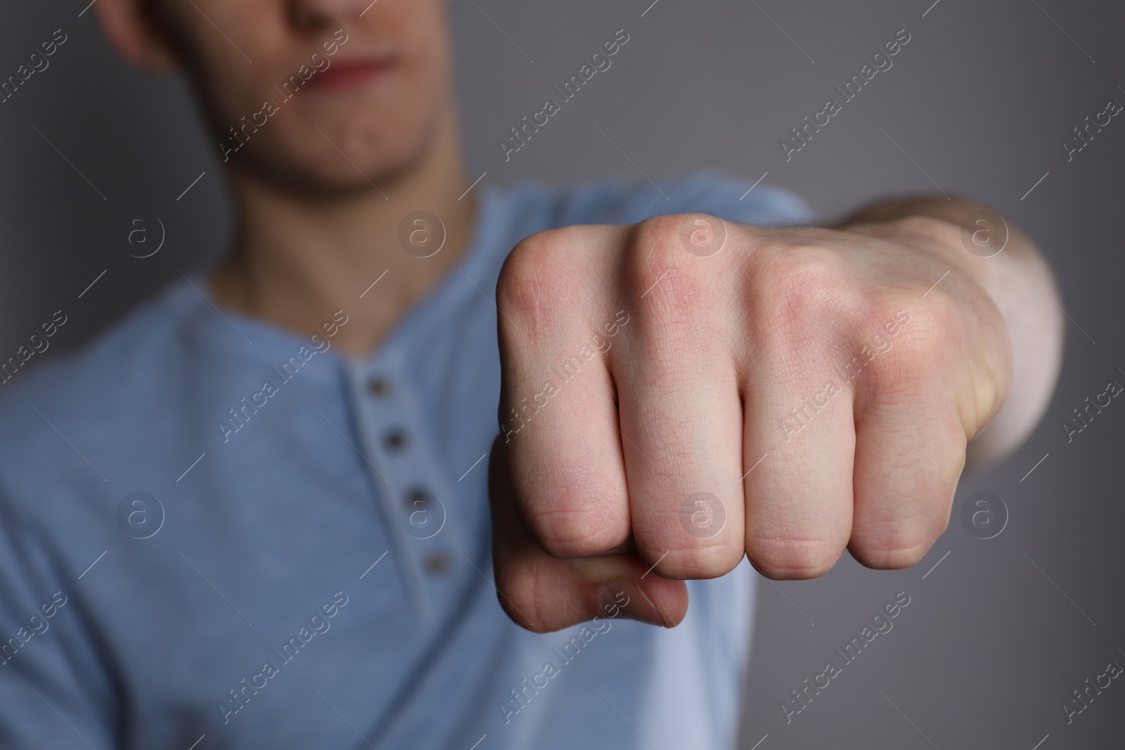 Photo of Man showing fist with space for tattoo on grey background, selective focus