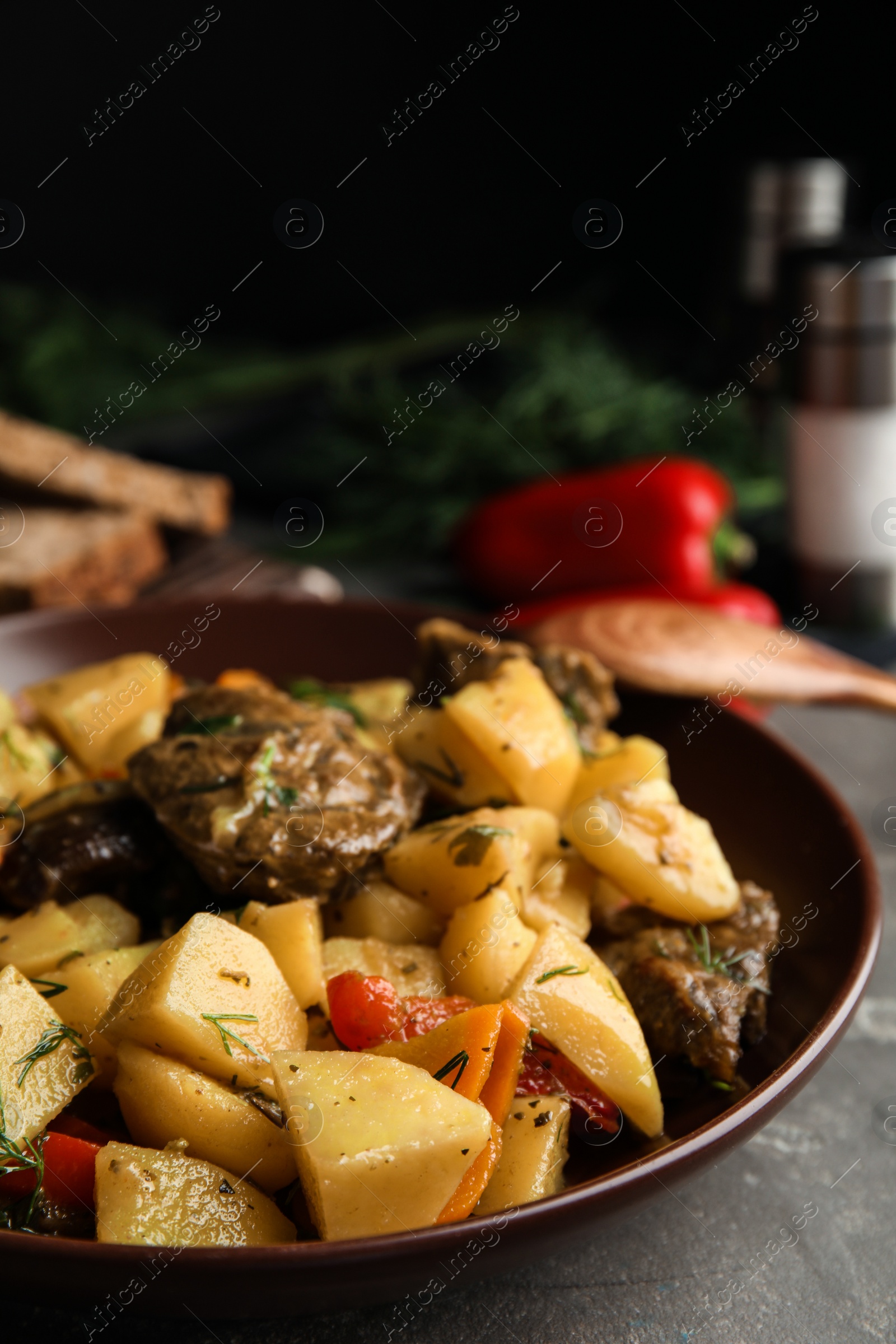 Photo of Tasty cooked dish with potatoes in earthenware on grey table
