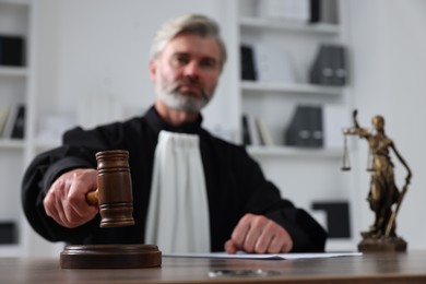 Photo of Judge with gavel and papers sitting at wooden table in office, selective focus