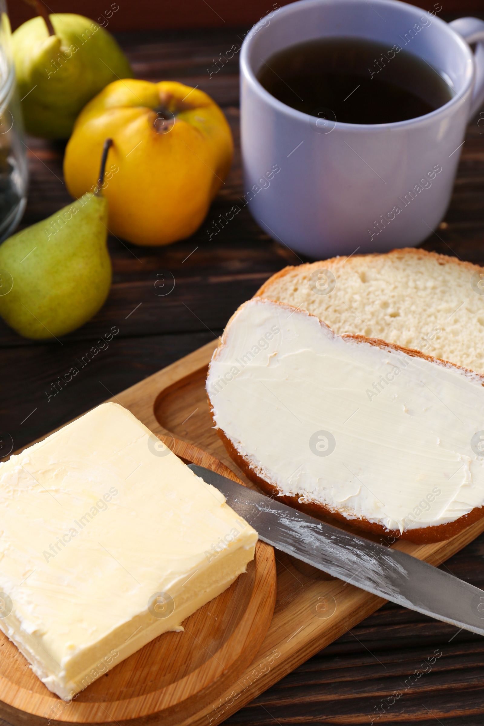 Photo of Tasty homemade butter, bread slices and tea on wooden table