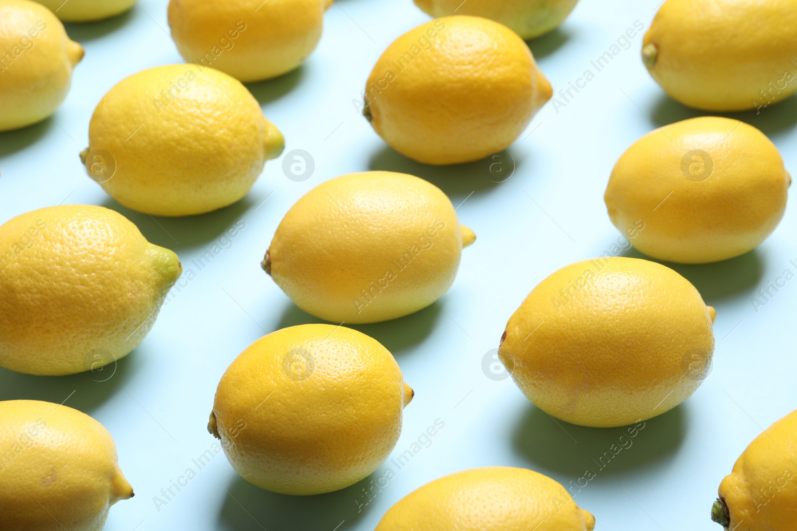 Photo of Many fresh ripe lemons on light blue background