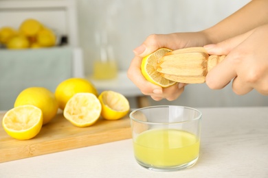 Photo of Woman squeezing lemon juice with reamer at white wooden table, closeup. Space for text