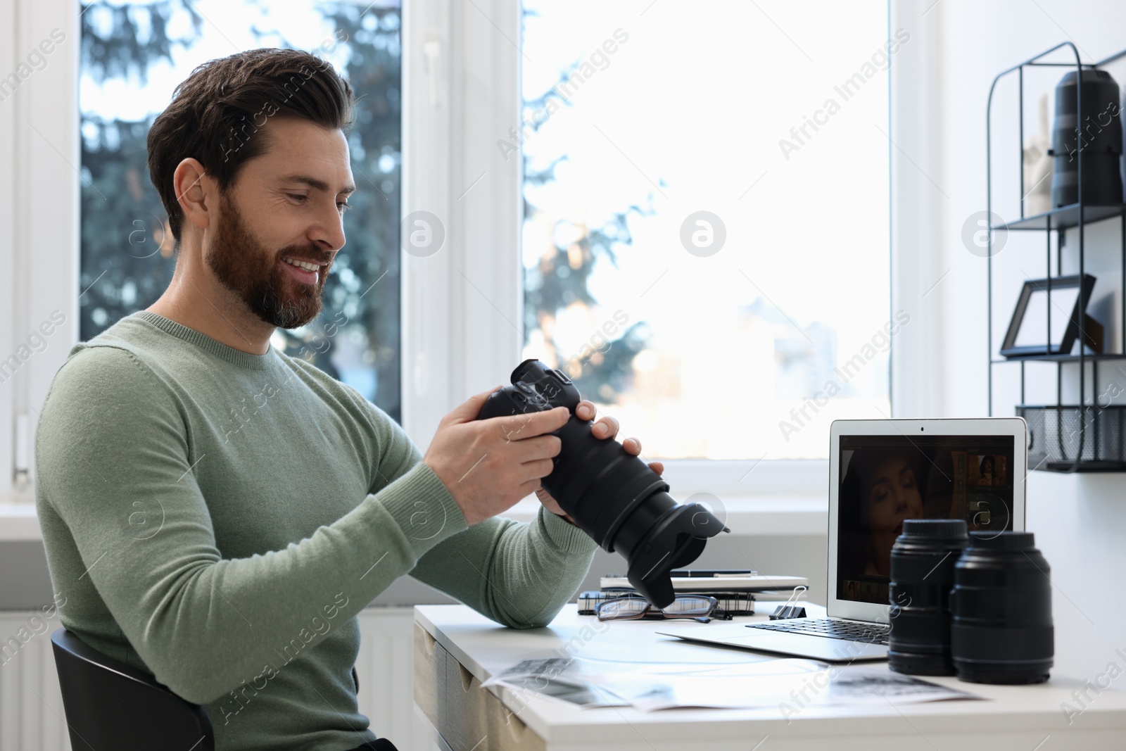 Photo of Professional photographer with digital camera at table in office