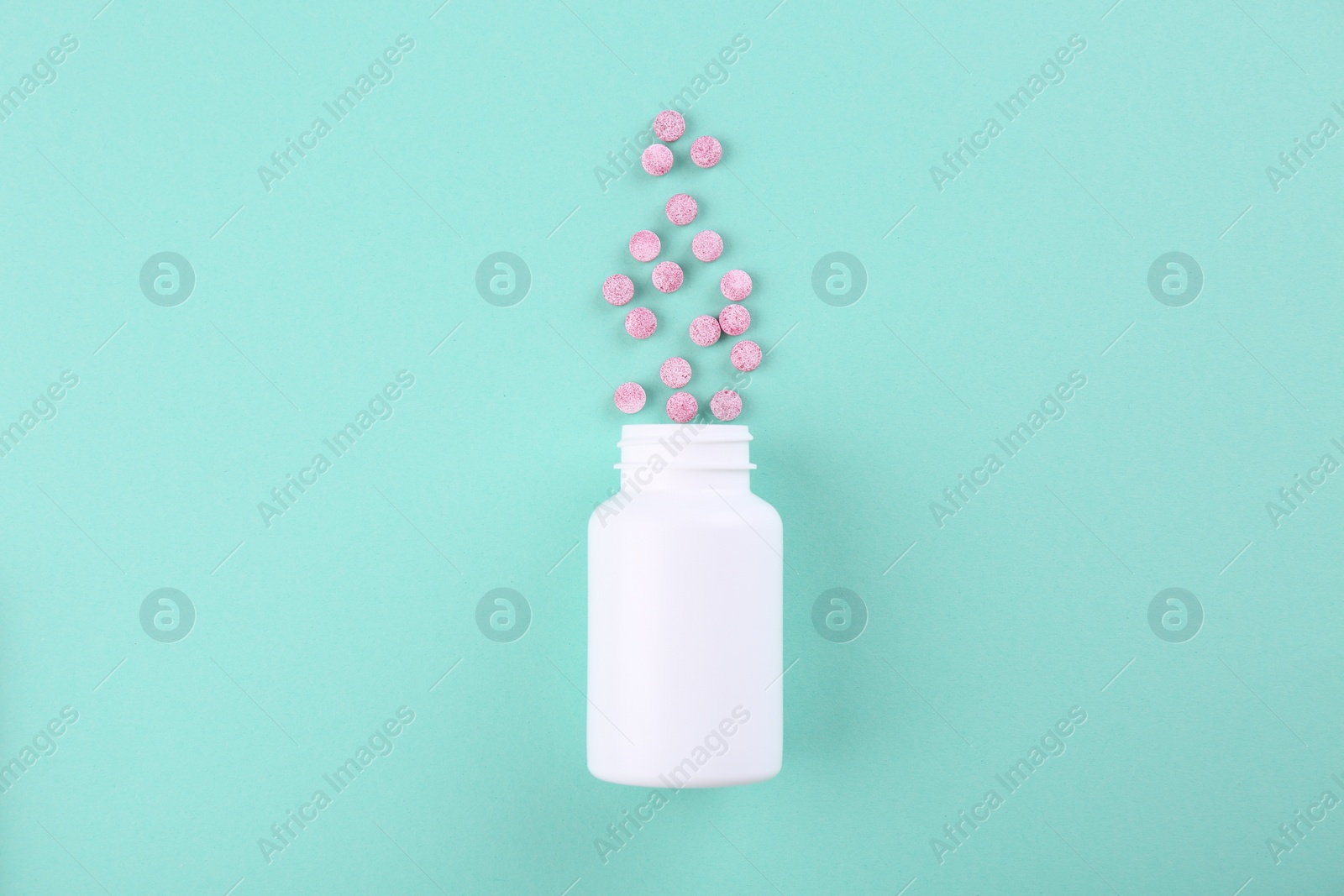 Photo of Bottle and vitamin pills on turquoise background, top view