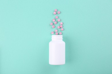 Bottle and vitamin pills on turquoise background, top view