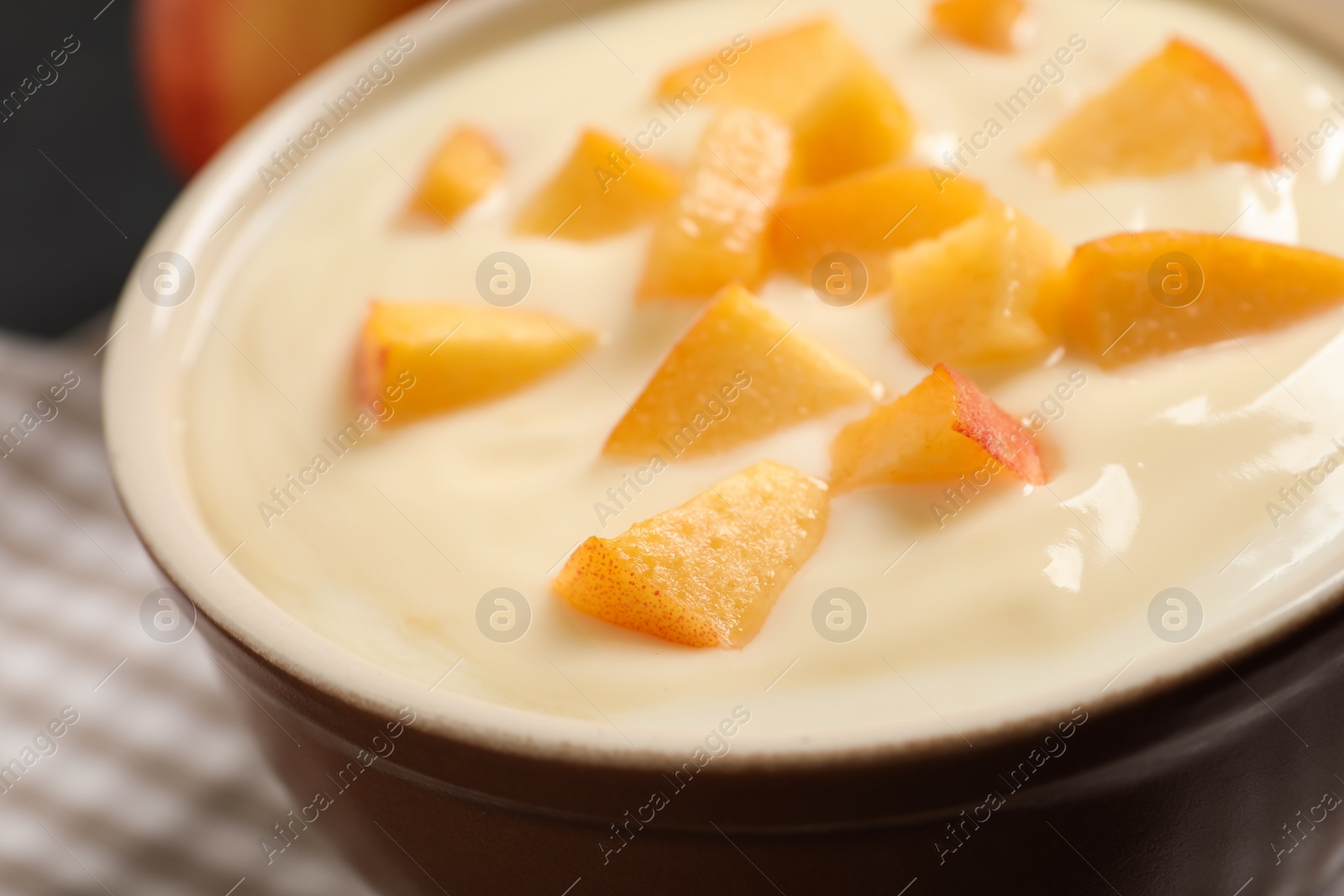 Photo of Delicious yogurt with fresh peach in bowl, closeup