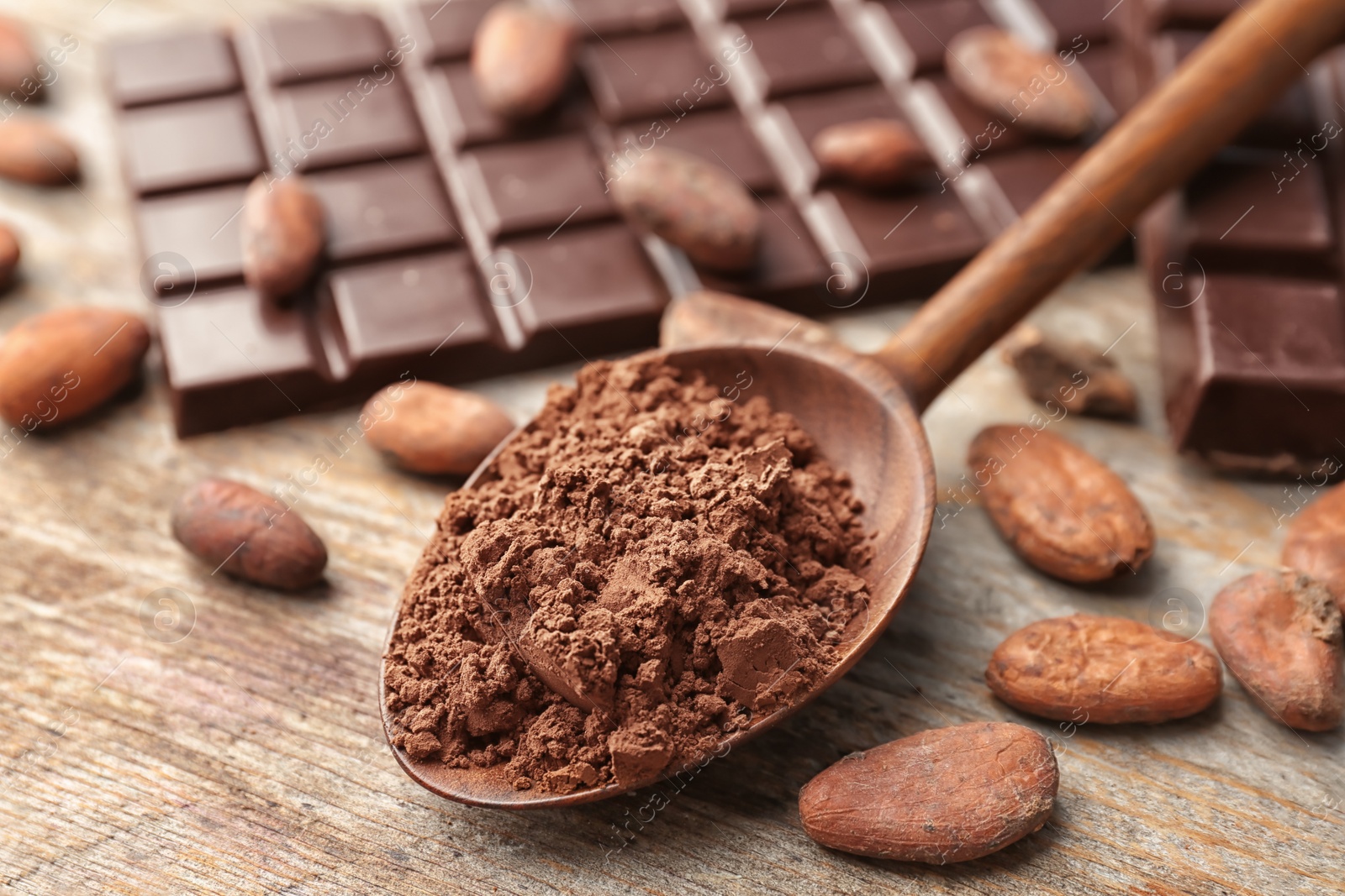 Photo of Composition with cocoa powder, beans and chocolate bar on wooden background