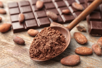 Photo of Composition with cocoa powder, beans and chocolate bar on wooden background
