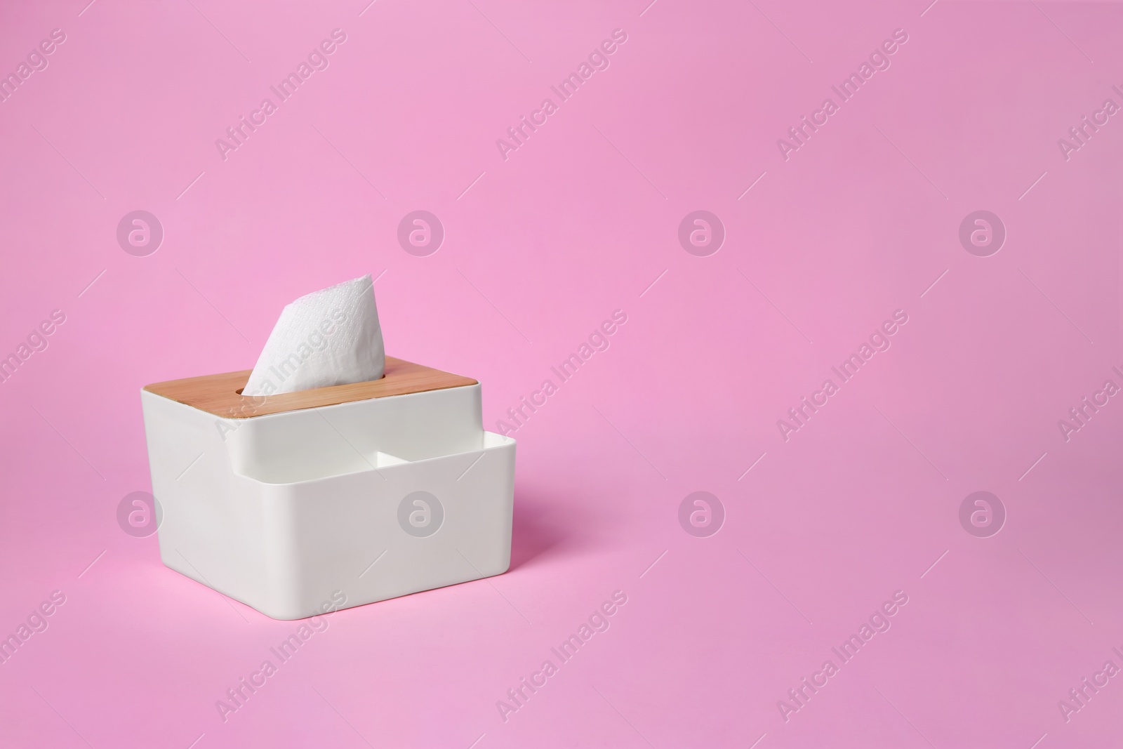 Photo of Holder with paper tissues on pink background. Space for text