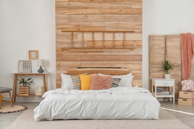 Photo of Stylish room interior with comfortable bed near wooden wall