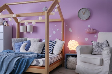 Photo of Child's room interior with comfortable bed and garland