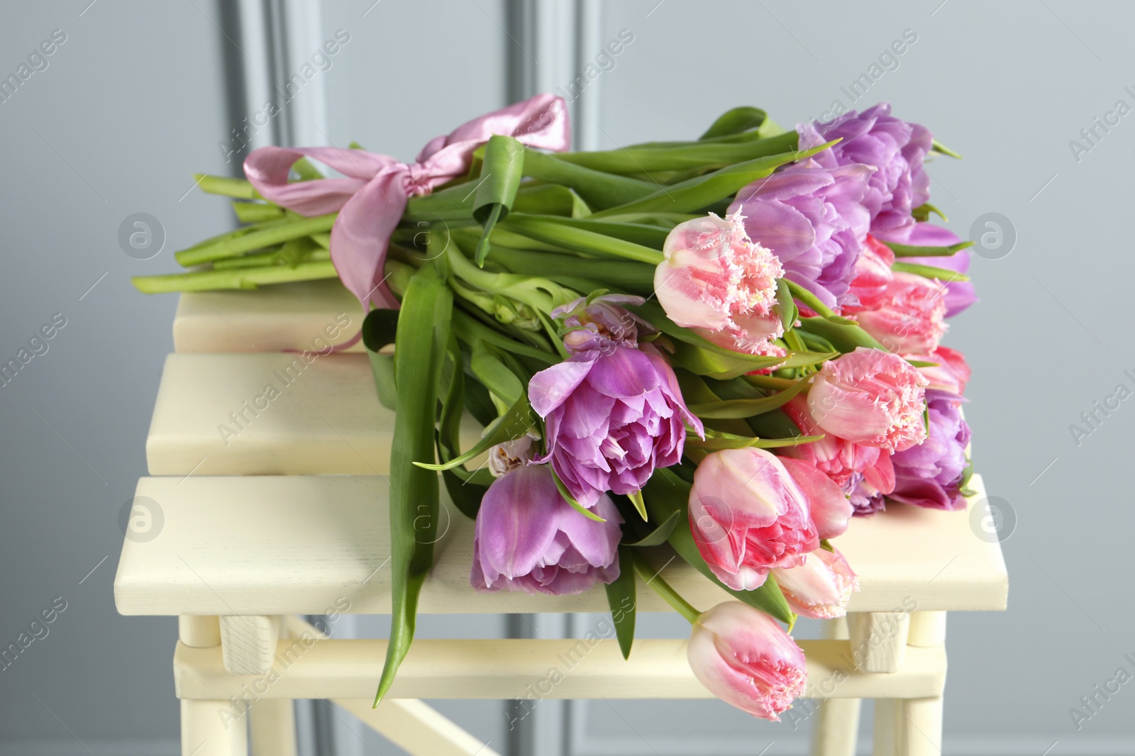 Photo of Beautiful bouquet of colorful tulip flowers on stool