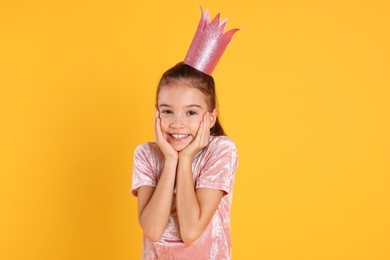 Photo of Cute girl in pink crown on yellow background. Little princess
