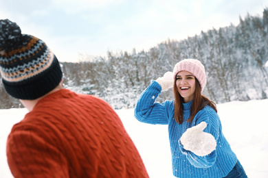Photo of Happy couple playing snowballs outdoors. Winter vacation