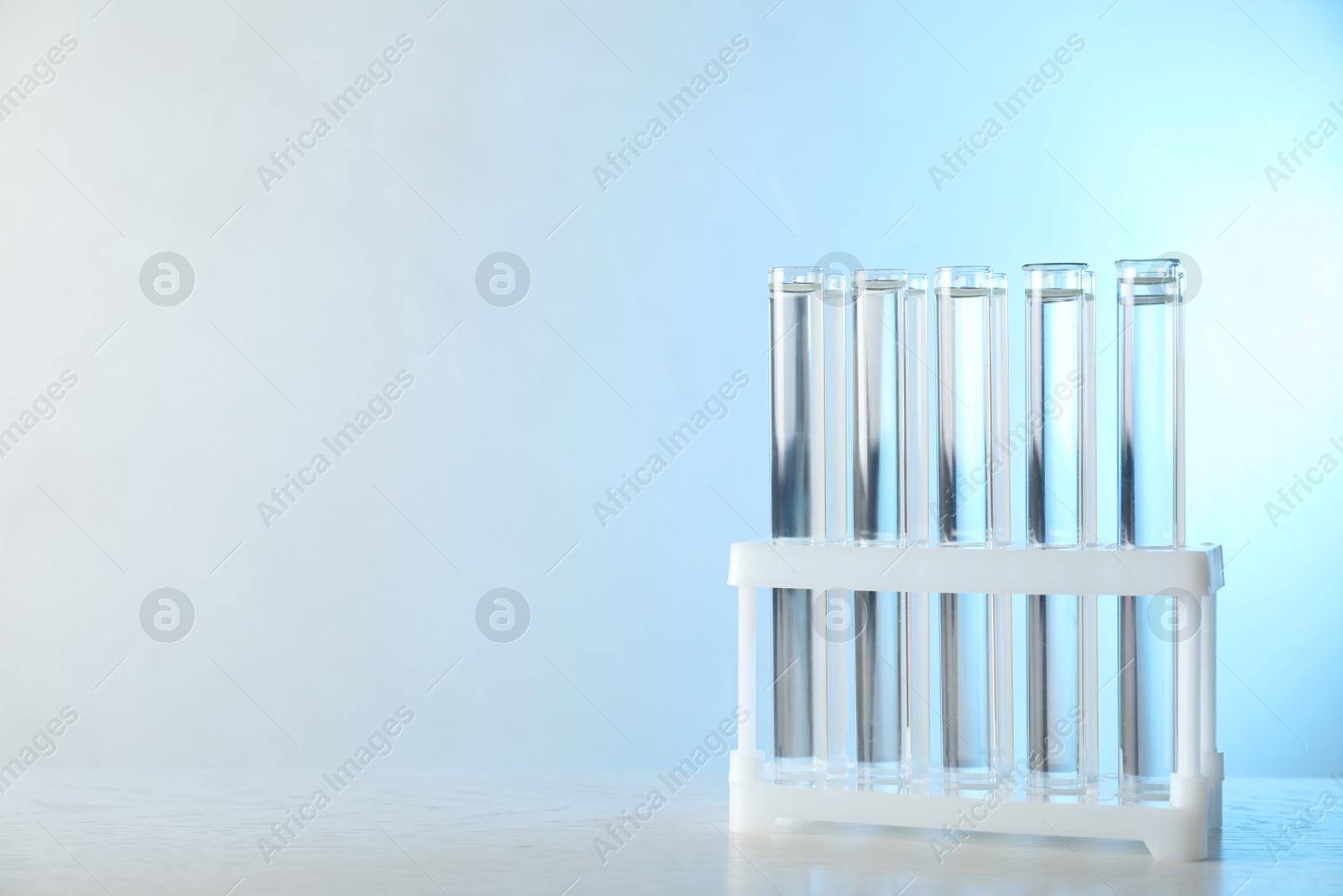Photo of Test tubes with liquid samples on table against toned blue background, space for text. Laboratory analysis