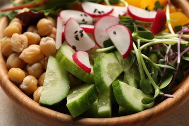Photo of Delicious vegan bowl with cucumbers, chickpeas and radish on beige table, closeup