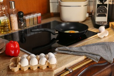 Frying eggs for breakfast in kitchen, selective focus